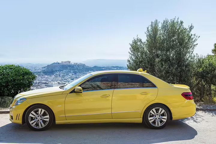 Yellow sedan private transfer for Athens Airport to Athens hotels arrival, parked with Acropolis view in Athens