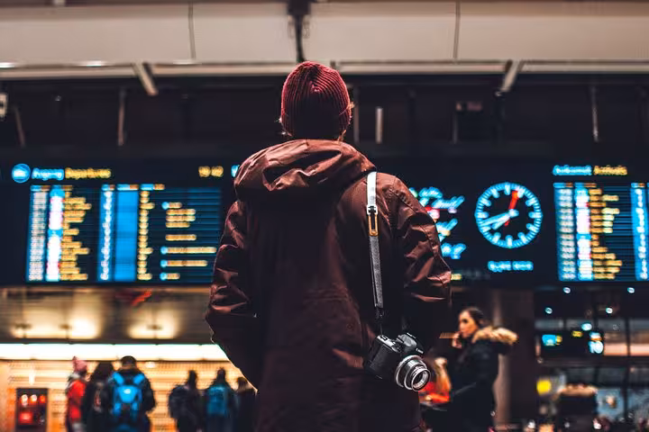 Traveler checks flight boards at Athens Airport, ready for luxury private transfer to Athens hotel downtown