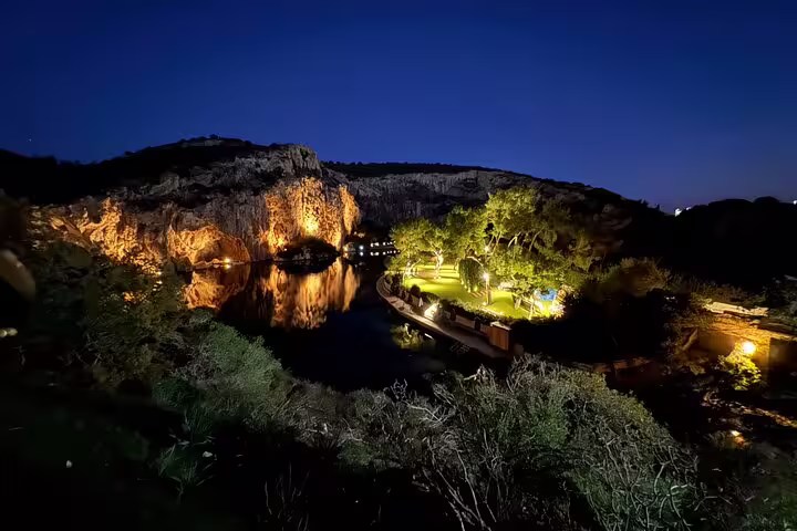 Athens Airport to city center private transfer with luxury chauffeur, scenic night view of illuminated lake and cliffs