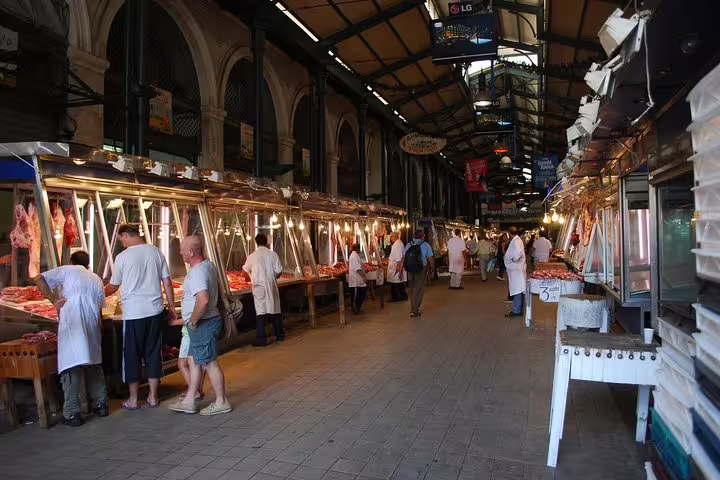 Athens Central Market meat hall stalls on a small-group morning food tour, bustling with local vendors