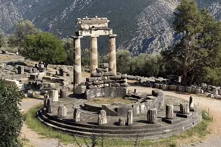 Ancient ruins of the Tholos of Delphi surrounded by lush greenery on a 2-day tour from Athens to Delphi and Meteora.