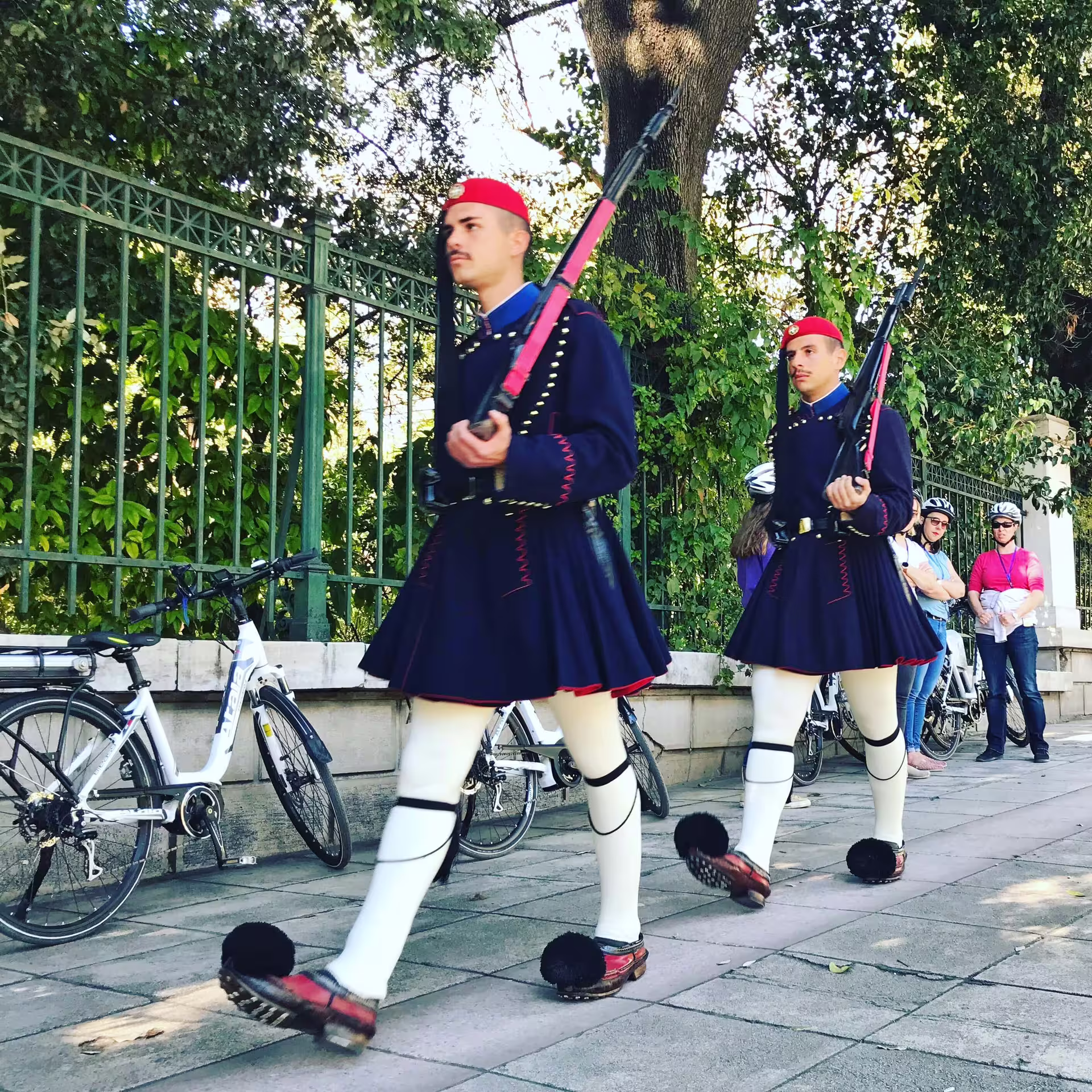 Traditional guards march past e-bikes in Athens, highlighting cultural heritage on an e-bike shore excursion tour.