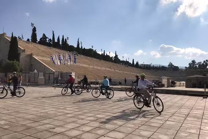 Group of cyclists exploring the historic Panathenaic Stadium in Athens under a clear blue sky on an e-bike tour.