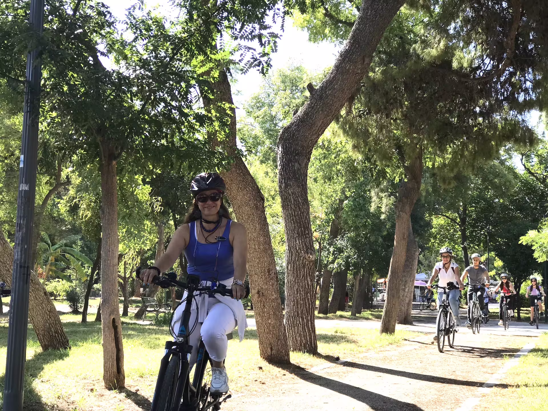 Group enjoying an e-bike ride through a scenic park in Athens, surrounded by lush greenery and sunshine.