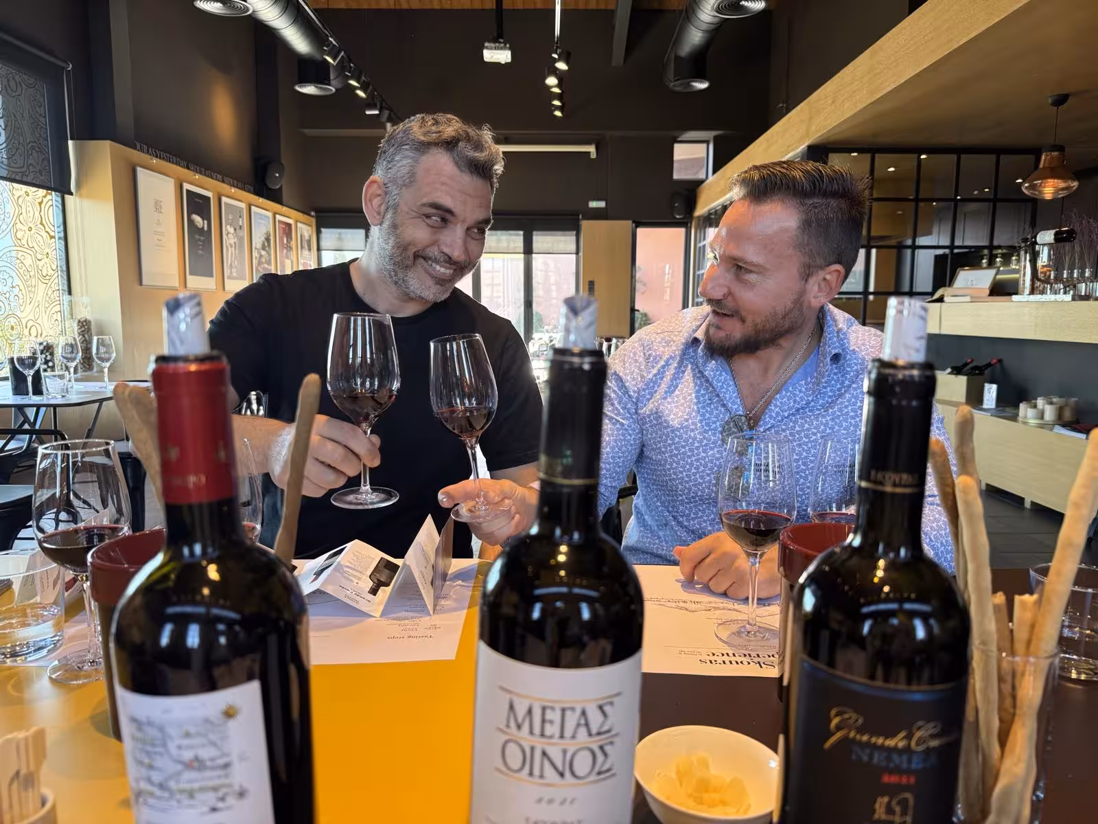 Guests clink red wine glasses at a modern Athens wine bar during an evening Greek wine tasting tour