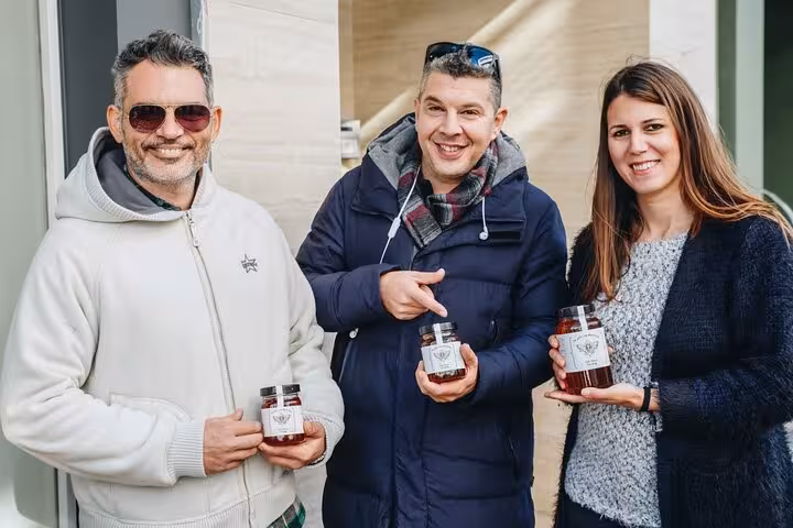 Guests on an Athens traditional food tour holding jars of Greek honey preserves during a tasting experience
