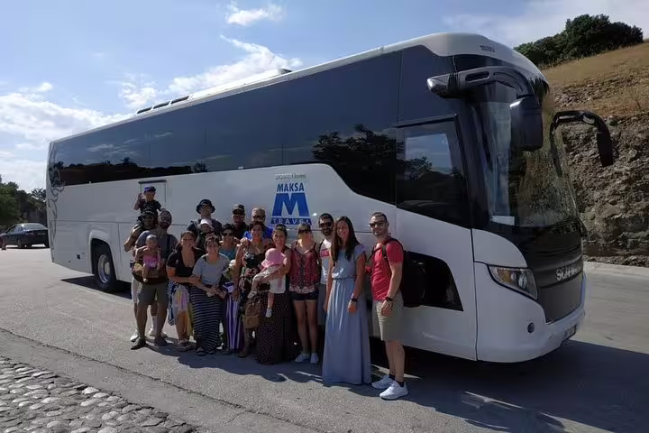 Group of tourists posing in front of a tour bus during a private day trip from Athens to Meteora, Greece.