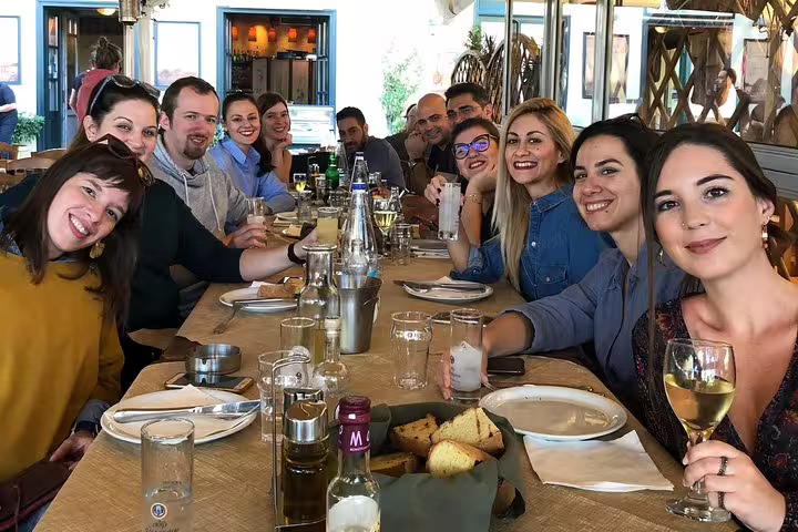 Group enjoying Greek lunch and wine at a local taverna during a private Athens to Nafplio Peloponnese day trip