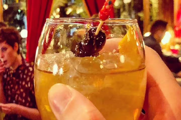Hand holding Greek cocktail in Athens bar, small group evening sightseeing with drinks and food tasting