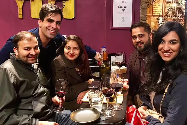 Small group Athens by night tour guests enjoying wine, drinks and Greek food tasting in a cozy bar