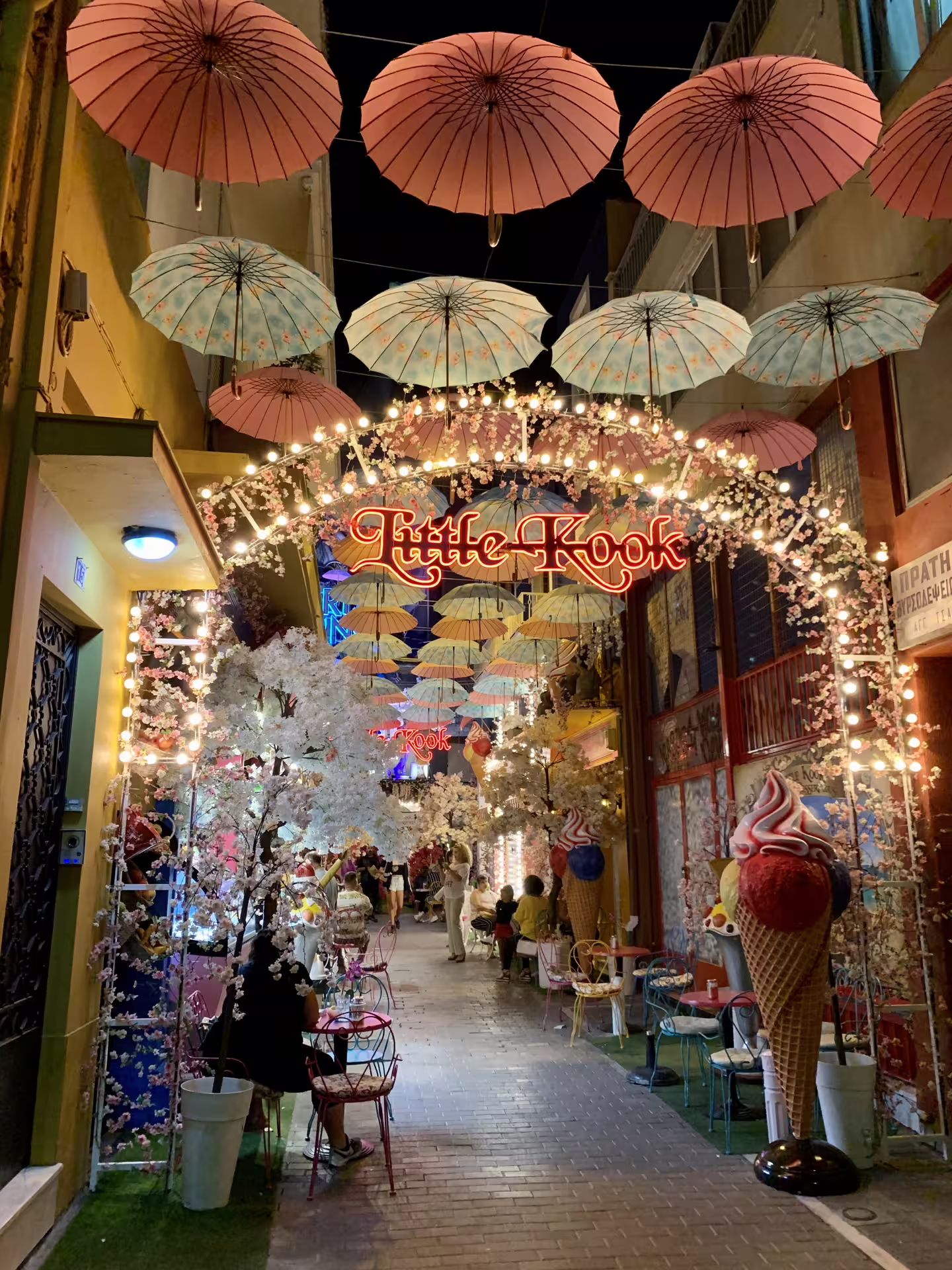 Colorful Athens alley with hanging umbrellas and cafe lights, ideal for airport to Piraeus private transfer