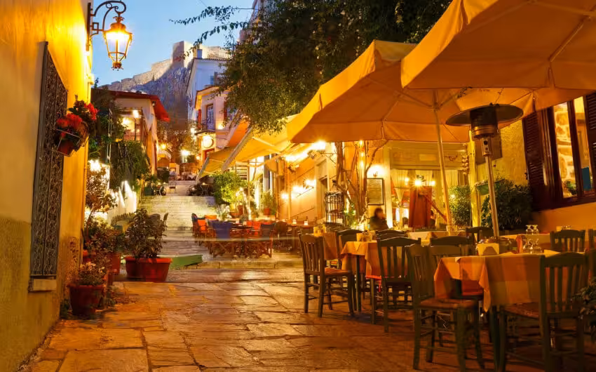 Warm-lit Plaka taverna street in Athens at night, ideal scene for a gyros and loukoumades tasting stroll