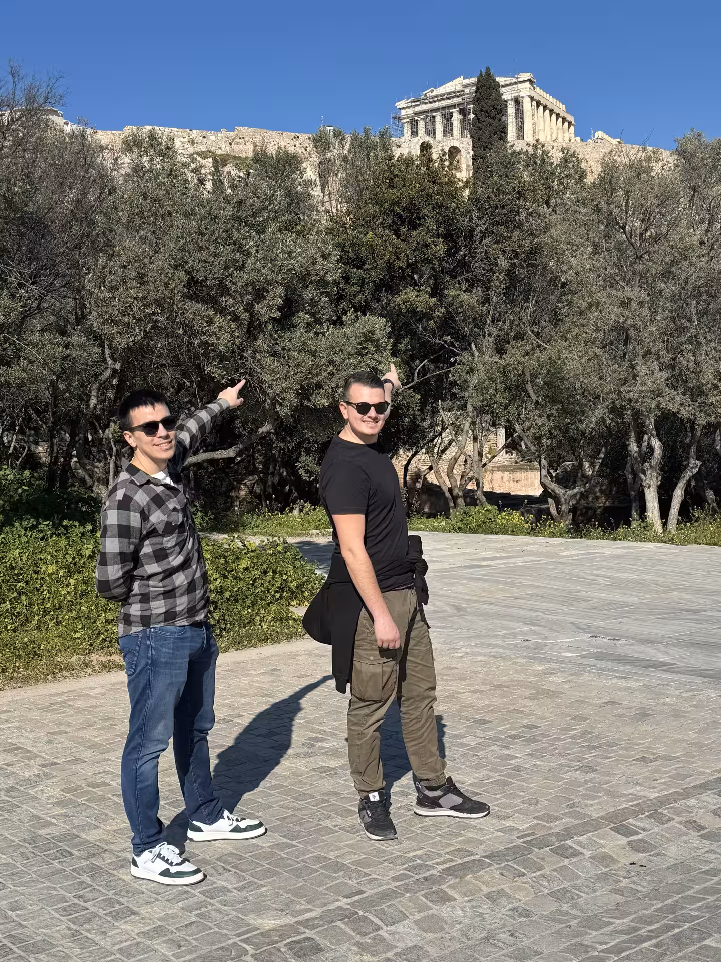 Travelers point to the Acropolis and Parthenon viewpoint on a private Athens car tour under blue skies