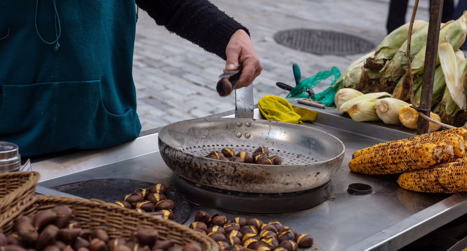 Street vendor roasting chestnuts beside grilled corn, a classic tasting on the Taste of Athens small-group afternoon food tour