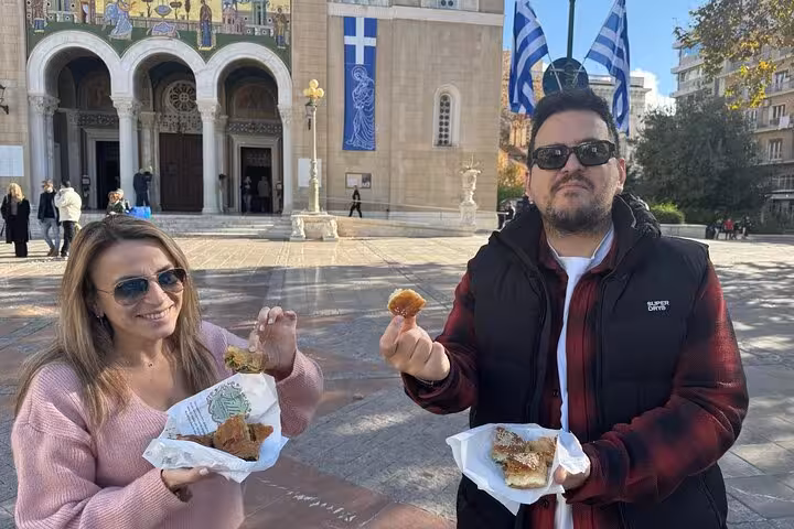 Guests sampling Greek pastries in central Athens square during an Athens traditional food tour