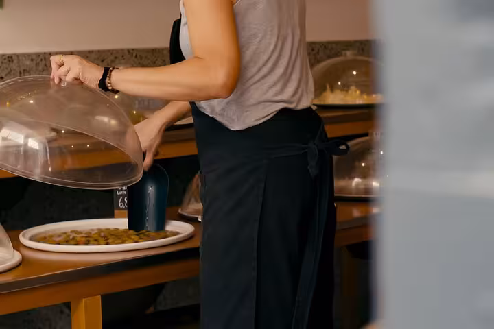 Guide lifting a cloche to reveal Greek meze tasting on a small group Athens walk and taste shore excursion