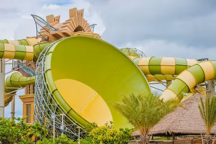 Atlantis Aquaventure Dubai Super Pass view of giant green water slide bowl with tropical palms at Palm Jumeirah