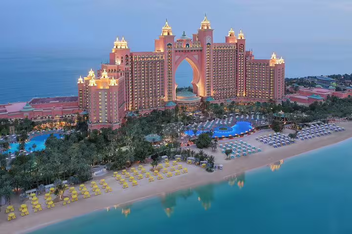 Aerial view of Atlantis The Palm hotel with illuminated towers, pools, and private beach during the Dubai tour.