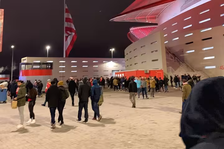 Fans arriving at Civitas Metropolitano stadium at night for an Atletico Madrid game experience with local