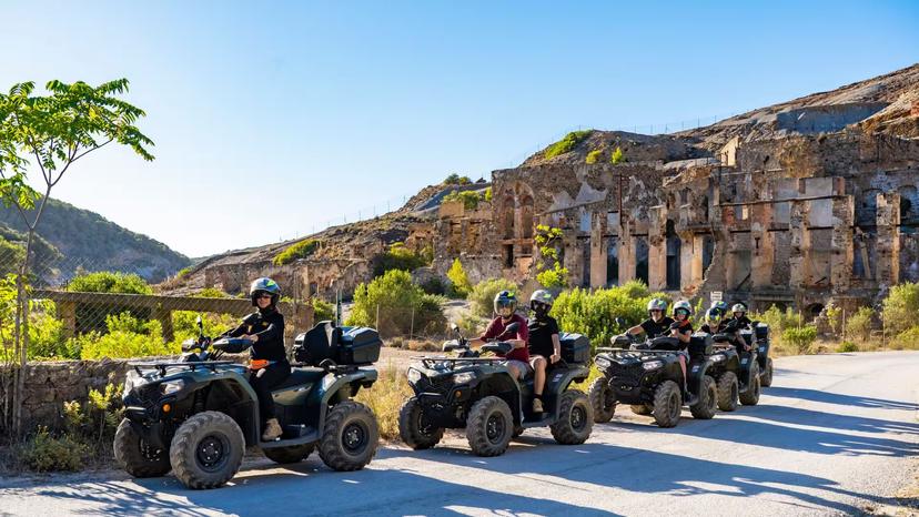Group enjoying ATV excursion in Costa Verde, Sardinia, with scenic views of historic ruins and lush greenery.