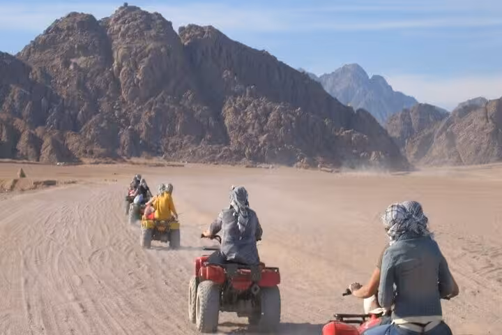 ATV quad bikes driving through Hurghada desert mountains on amazing safari tour with dust trails