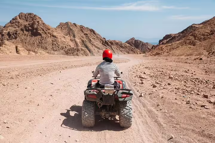 Rider on ATV quad bike driving through Sinai desert mountains on Sharm El Sheikh safari adventure tour