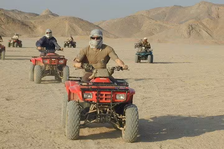 Riders driving quad bikes across Sharm El Sheikh desert mountains on Super Safari ATV adventure with Bedouin camp