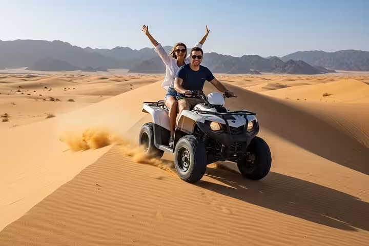 ATV quad bike safari in Sharm El Sheikh, couple racing over sand dunes with Sinai mountain backdrop