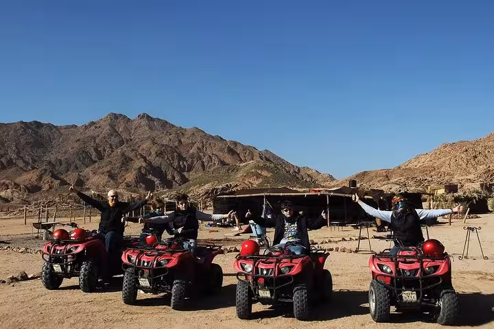 Group posing on red quad bikes at a Bedouin camp stop during an ATV desert safari in Sharm El Sheikh, Sinai