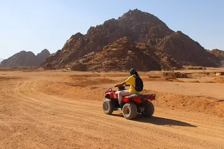 Solo ATV rider on Super Safari quad tour from Sharm El Sheikh, cruising Sinai Desert track by rocky hills