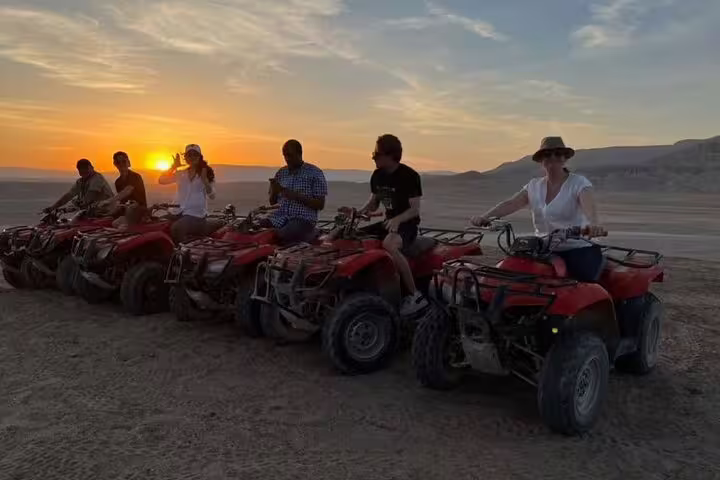 Tourists lined up on ATVs at sunset in Hurghada desert, part of quad bike safari with camel ride, dinner and show
