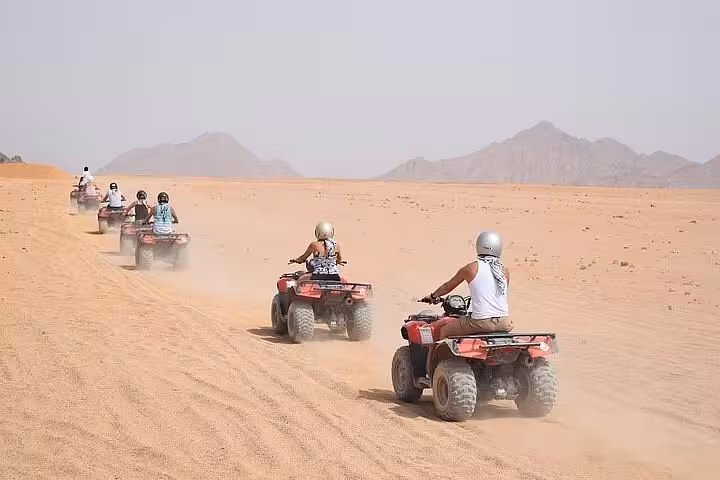 ATV quad safari convoy in Sharm El Sheikh desert, dusty trail toward Sinai mountains before Bedouin dinner