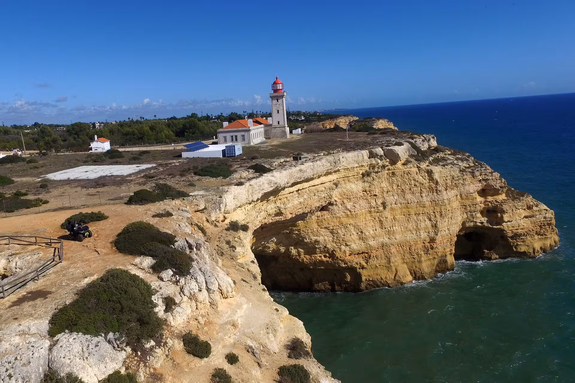 Aerial view of a lighthouse perched on dramatic cliffs overlooking the ocean in the seven Hanging Valleys tour.