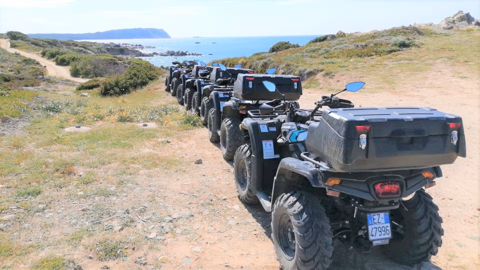 Line of ATVs ready for an adventure in Santa Teresa di Gallura with stunning coastal views.
