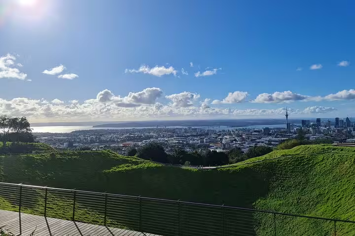 Expansive view of Auckland cityscape and harbor under a bright, sunny sky from Mount Eden.
