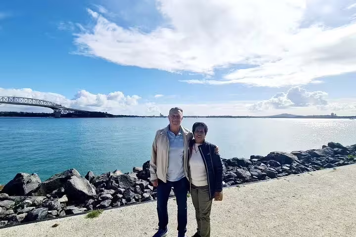 Visitors posing by the waterfront with a view of Auckland Harbour Bridge on the Highlight Day Tour.