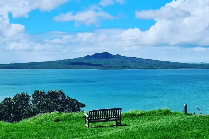 Serene bench view overlooking Rangitoto Island across blue waters, ideal stop on a private Auckland highlight tour.