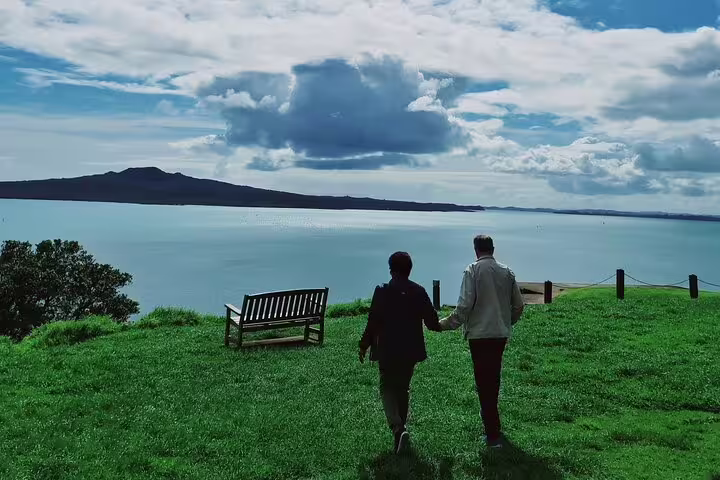Couple walking towards a scenic view of Rangitoto Island from Auckland, enjoying a serene half-day tour.