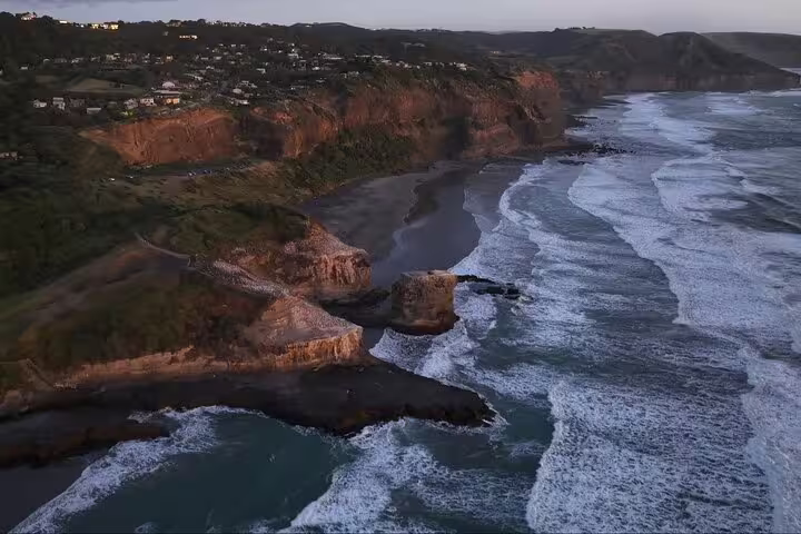 Auckland's rugged coastline at dusk, showcasing breathtaking cliff views on a romantic sunset tour with winery and thermal pool.