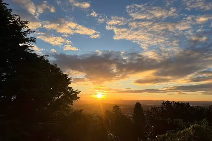 Sunset over Auckland hills with vibrant skies and lush greenery, perfect for romantic winery and outdoor experiences.