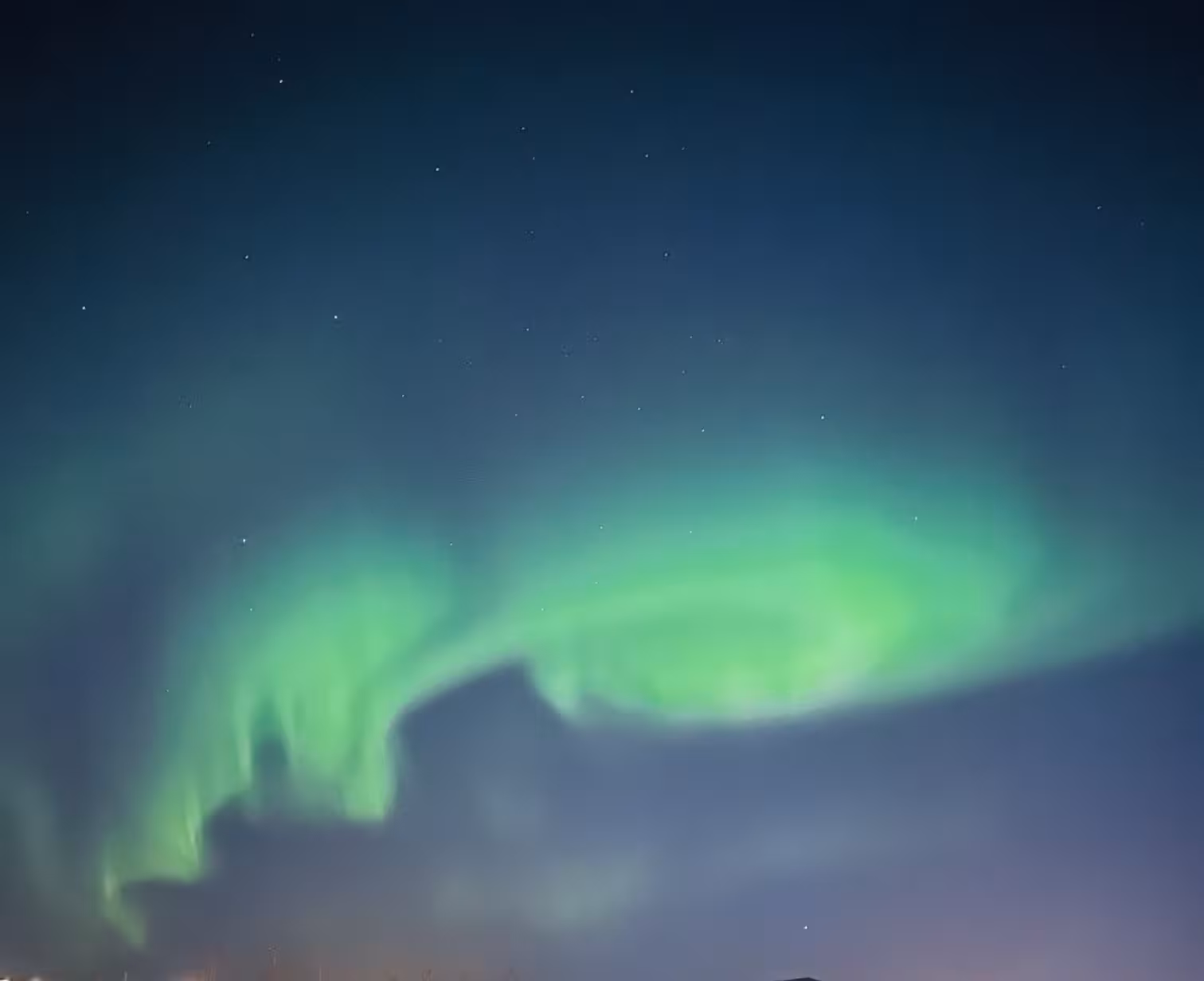 Vivid aurora borealis swirl in green over star-filled sky, unforgettable Northern Lights viewing on Arctic tour