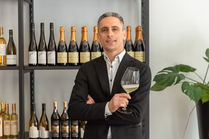 Sommelier holding a glass of Austrian white wine in a Vienna tasting room with bottle display behind