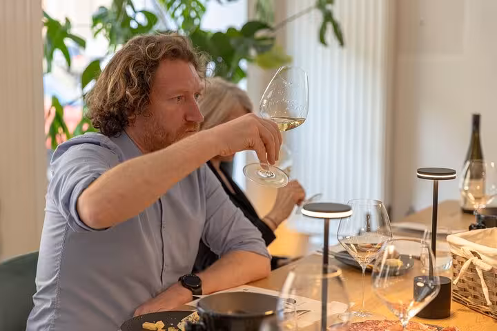 Guest swirling Austrian white wine during Vienna wine tasting tour at a modern tasting room table