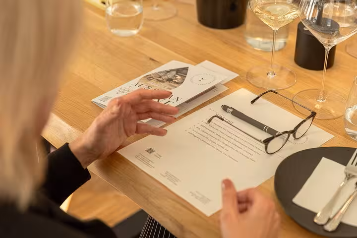 Guest reviewing tasting notes at an Austrian wine tasting, with wine glasses, pen and menu on table