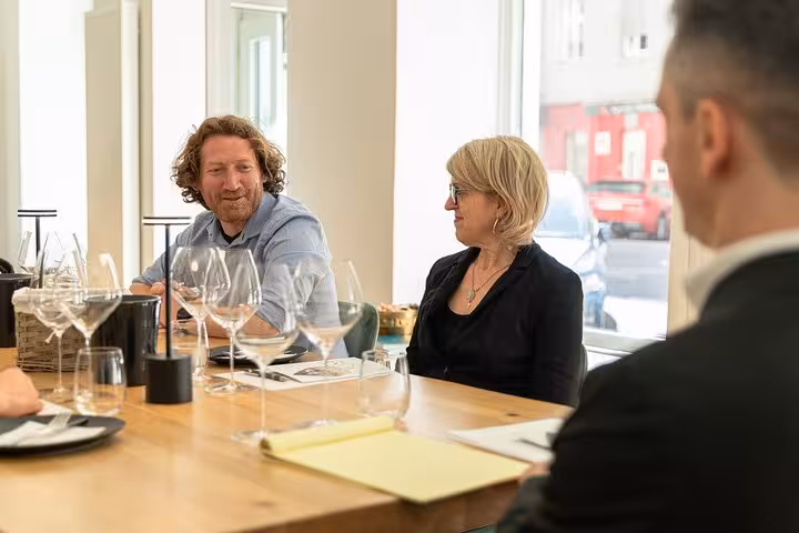 Guests chatting at a Vienna Austrian wine tasting with crystal glasses, guided winery experience indoors