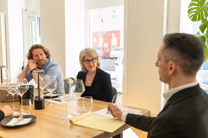 Guests listening to a wine expert during an Austrian wine tasting in Vienna, seated at a table with glasses