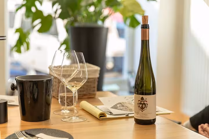 Austrian wine tasting setup with white wine glasses and bottle on a wooden table in a cozy venue