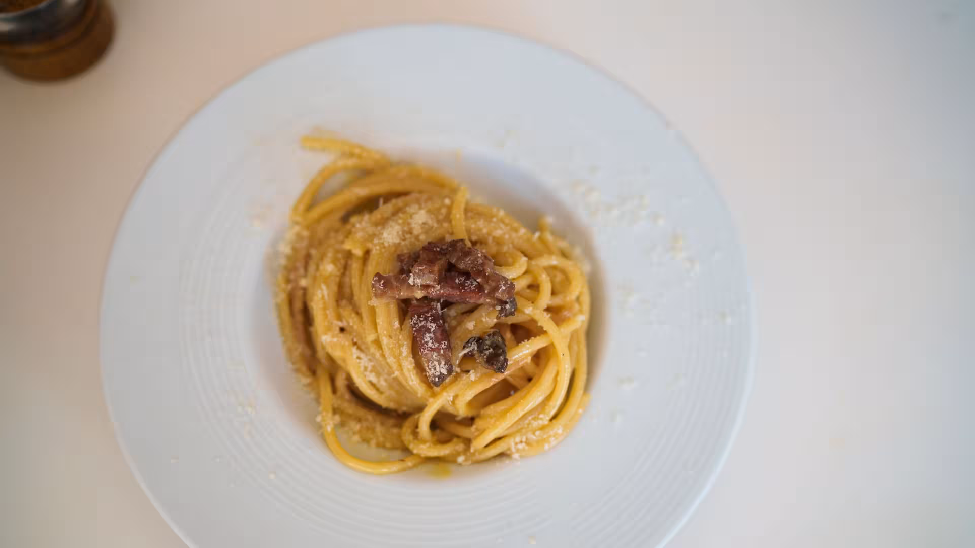 Plate of authentic pasta carbonara garnished with pancetta, showcasing Italian culinary tradition in Olbia cooking class.