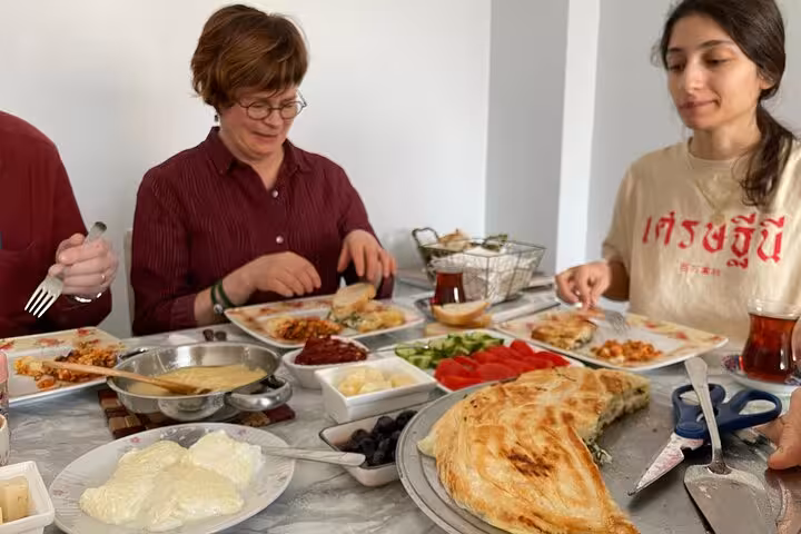 Friends sharing authentic homemade Turkish breakfast with fresh bread, olives, cheese and tea at a local home