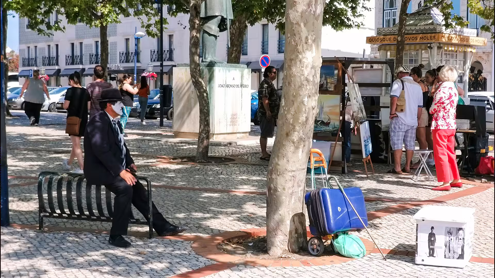 People explore an art market in Aveiro, Portugal, with a street performer nearby, capturing the vibrant culture of the area.